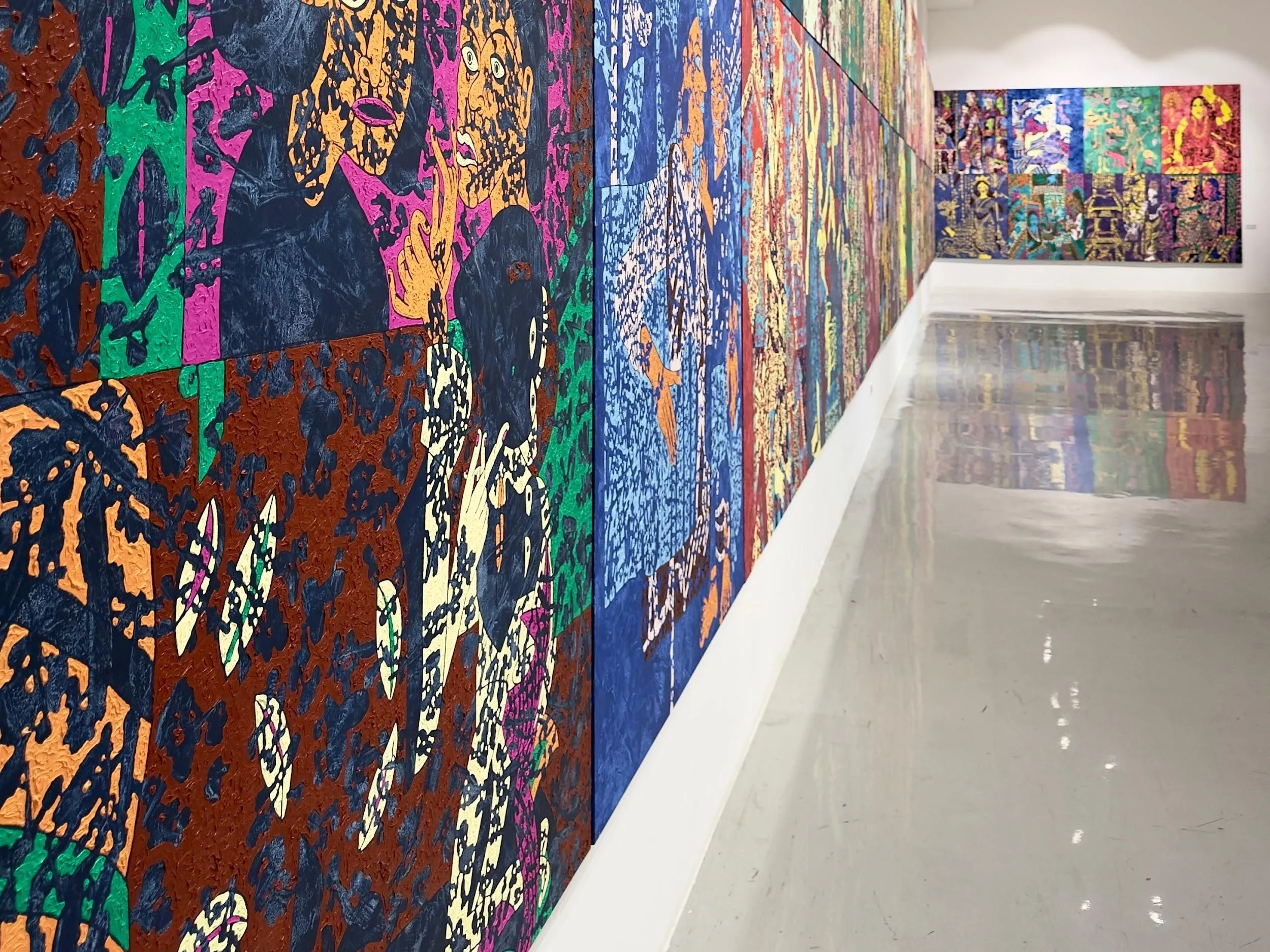 Paintings running the length of the gallery, doubled in the polished floor